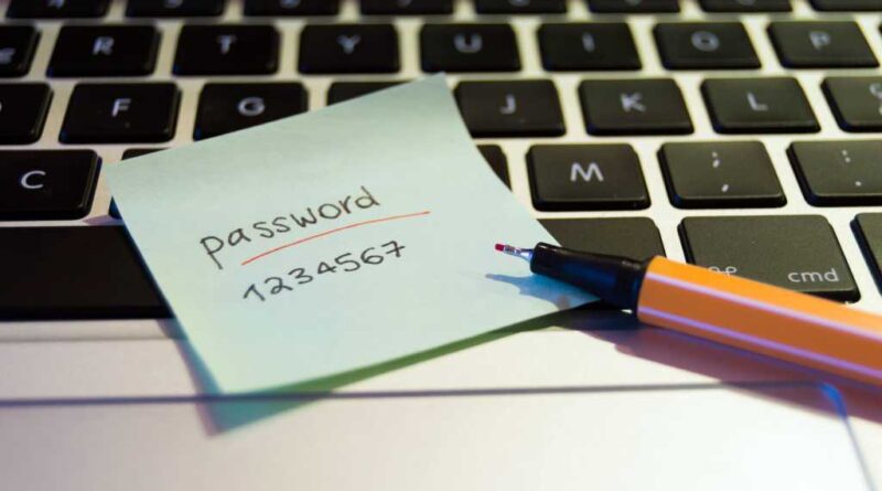 Laptop with pen and a post-it showing a weak password lying on top