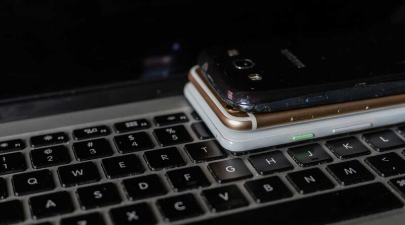 Three smartphones piled on a laptop keyboard