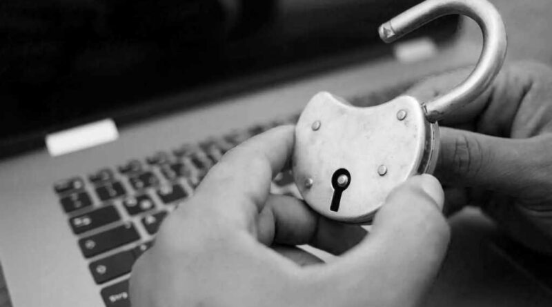 adult hands holding an open padlock in front of a laptop