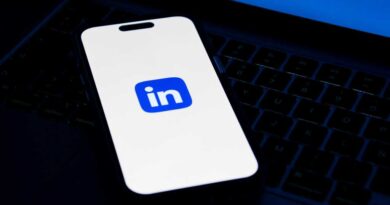 LinkedIn logo on phone screen sitting on laptop keyboard