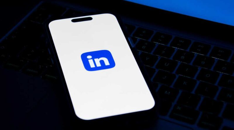 LinkedIn logo on phone screen sitting on laptop keyboard