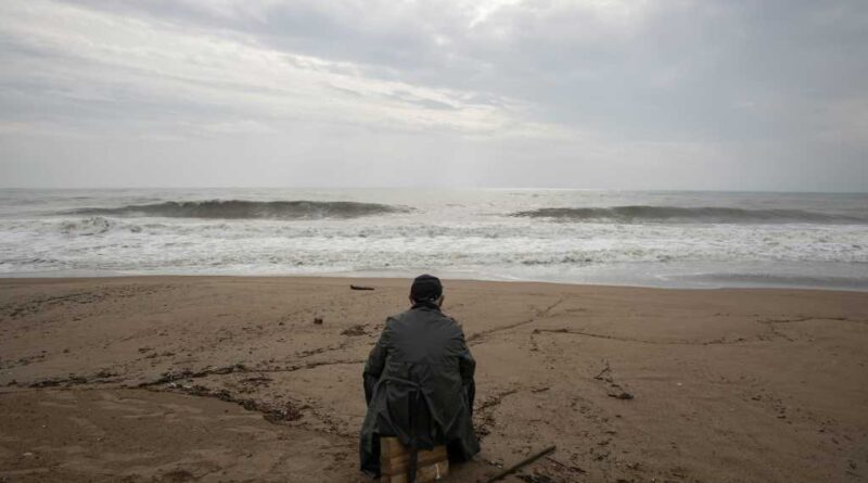 Lone traveler sitting on luggage on a beach's shores