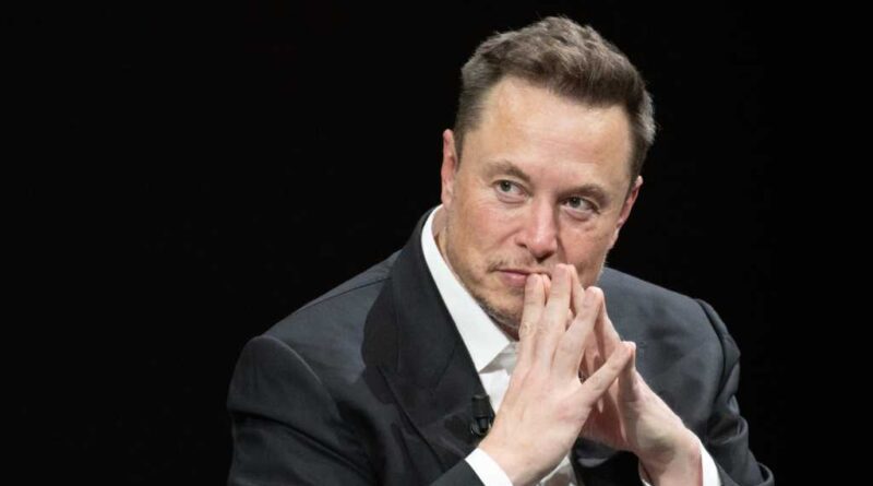 Elon Musk sitzend vor schwarzem Hintergrund