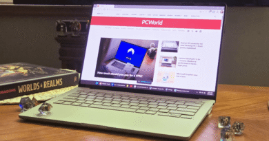 Asus Zenbook A14 laptop on table with dice and book