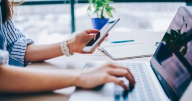 Woman with phone in one hand and laptop in the other