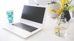 Acer Chromebook on white desk with flower in vase beside it