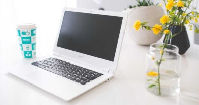 Acer Chromebook on white desk with flower in vase beside it