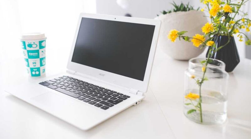 Acer Chromebook on white desk with flower in vase beside it