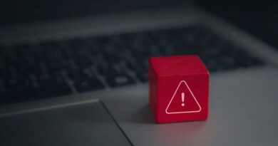 Red warning cube on a laptop keyboard in darkened room