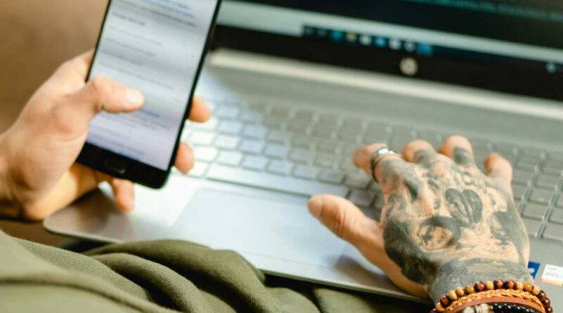 Man at a laptop with a phone in his hand