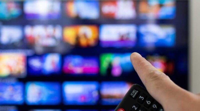 Man holding remote and pointing at smart TV with streaming options