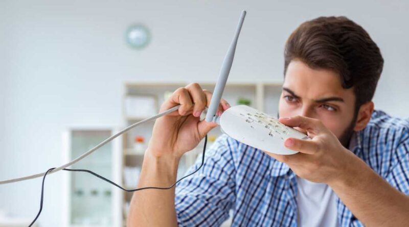 Mann checkt frustriert seinen WLAN-Router
