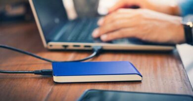 External SSD/HDD on a table next to a notebook/laptop, man typing on keyboard