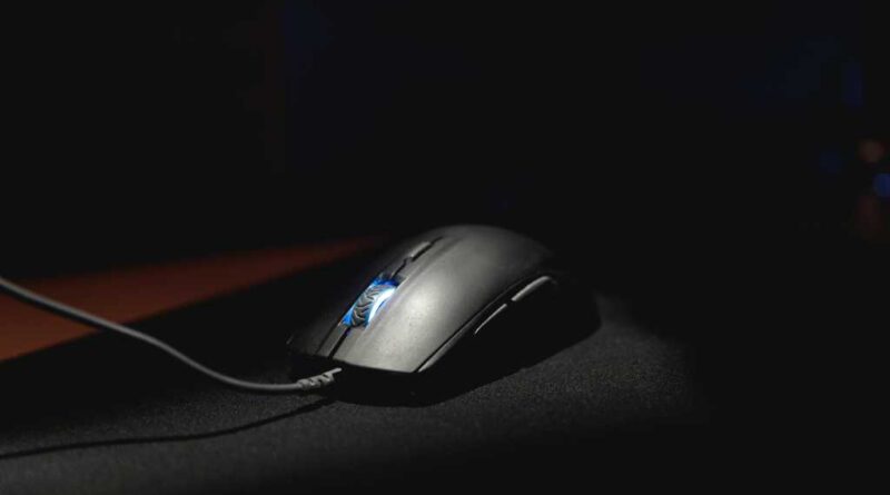 A computer mouse lit dramatically on a black mouse mat
