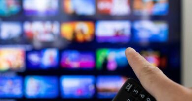Man holding remote and pointing at smart TV with streaming options