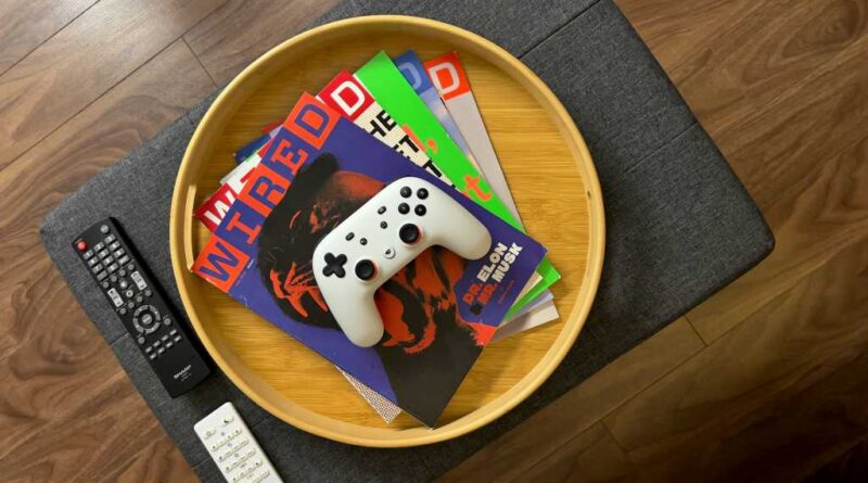 Wired magazines in a wood tray on a coffee table, with a controller on top of the stack