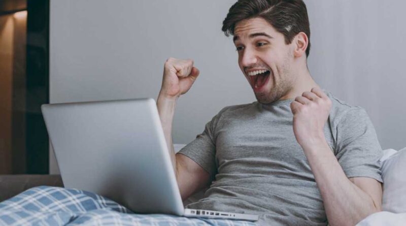 Laptop-Nutzer jubelt im Bett