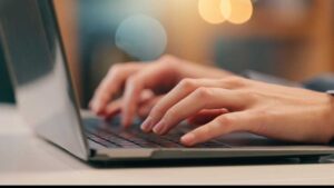 Eine Nahaufnahme eines Laptops/Notebooks, auf dem zwei Hände etwas tippen