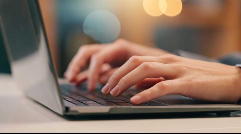 Eine Nahaufnahme eines Laptops/Notebooks, auf dem zwei Hände etwas tippen