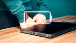 Laptop on wooden desk with empty battery icon indicator