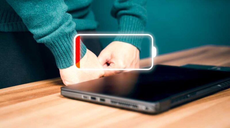 Laptop on wooden desk with empty battery icon indicator