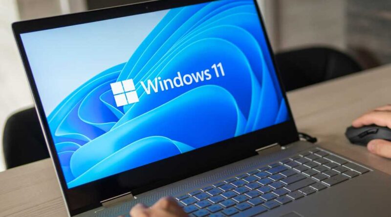 Man working on a Windows 11 laptop clearly on screen