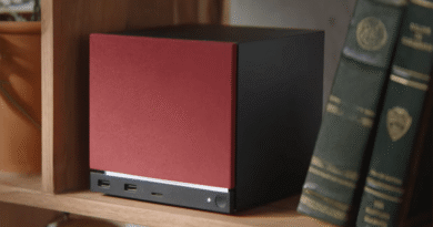 Steam Machine (2026) with red color faceplate on a bookshelf with two green books to its right
