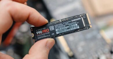Man holding Samsung 990 PRO SSD between fingers over exposed laptop hero