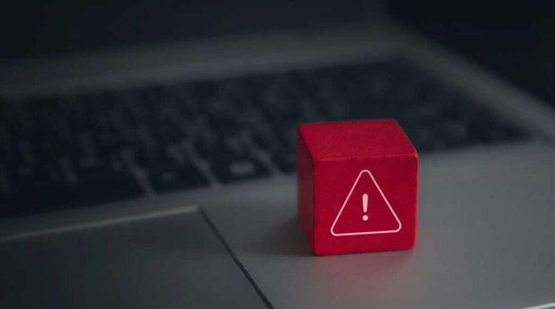Red warning cube on a laptop keyboard in darkened room