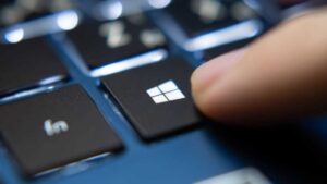 Finger pressing Windows key on a blue laptop keyboard