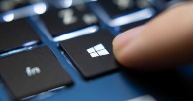 Finger pressing Windows key on a blue laptop keyboard