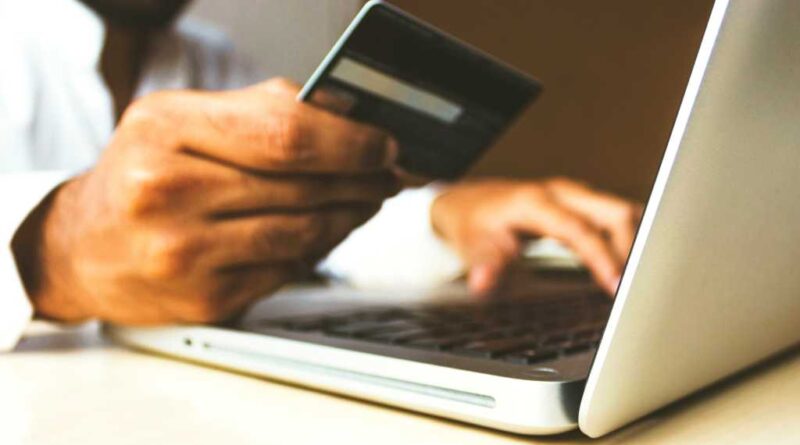 Man on laptop holding credit card making online purchase