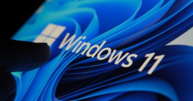 Finger touching Windows 11 logo on screen in dark room