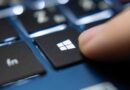Finger pressing Windows key on a blue laptop keyboard