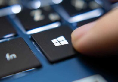 Finger pressing Windows key on a blue laptop keyboard