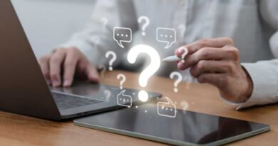 Man on laptop pointing to question marks and chat bubbles with stylus
