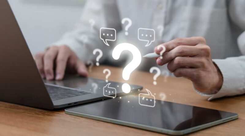 Man on laptop pointing to question marks and chat bubbles with stylus