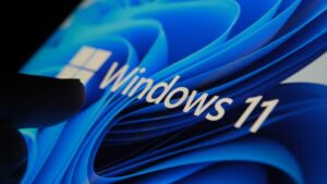 Finger touching Windows 11 logo on screen in dark room