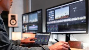 Ein Mann, der vor einem Computer mit zwei Bildschirmen ein Video editiert