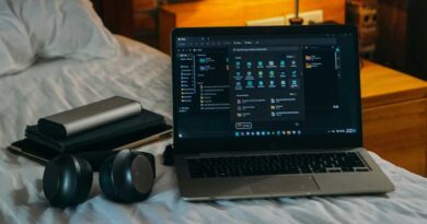Laptop headphones accessories on bed in dorm room