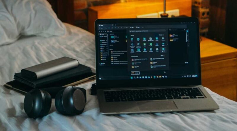 Laptop headphones accessories on bed in dorm room