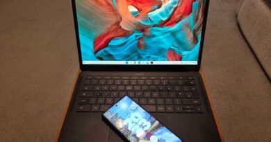 Chromebook laptop on a wooden tray desk with Android phone on keyboard