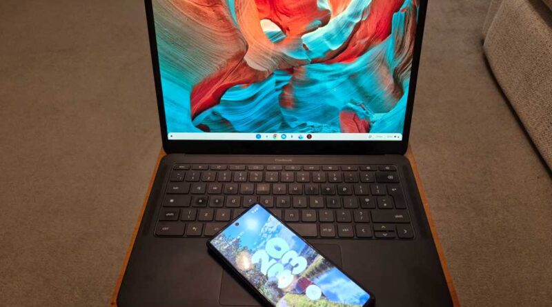 Chromebook laptop on a wooden tray desk with Android phone on keyboard