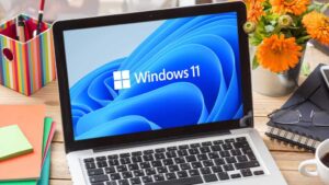Windows 11 laptop on a wooden desk workstation