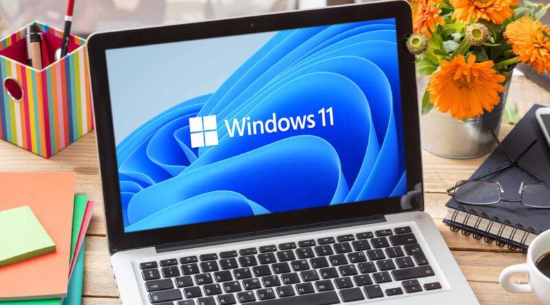 Windows 11 laptop on a wooden desk workstation