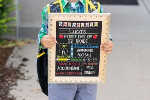 Child holding a "First Day of School" sign board