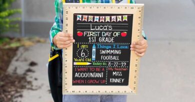 Child holding a "First Day of School" sign board