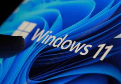 Finger touching Windows 11 logo on screen in dark room